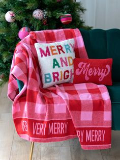 a red and white plaid blanket sitting on top of a green chair next to a christmas tree