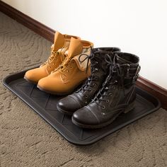 three pairs of boots sitting on top of a black tray