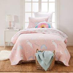 a pink bed with unicorns on it in a bedroom next to a white window