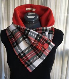 a black dress with a red and white plaid scarf around it's neck is shown in front of a window