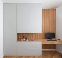 an office with white cabinets and wooden flooring, along with a computer on the desk