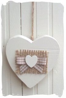 a white heart hanging on the side of a door with a bow tie attached to it