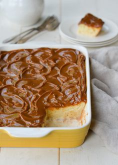 a yellow and white casserole dish filled with caramel swirl cake on a table