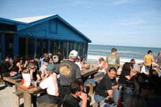 a group of people sitting at picnic tables on the beach