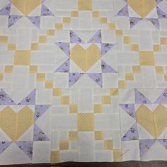 a yellow and white quilt with hearts in the center on it's back side