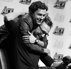 two men hugging each other while sitting in a chair at a press room for the avengers