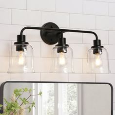 a bathroom vanity light with three clear glass shades on it's sides and a black metal frame