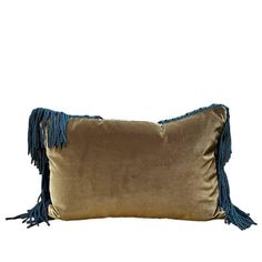 a gold and blue pillow with tassels on the side, against a white background