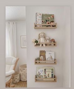 three wooden shelves with books on them in a white room next to a rocking chair