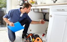 a man fixing a sink in a kitchen with tools on the floor next to it