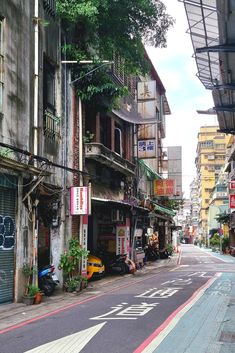 an empty city street with buildings on both sides and graffiti painted on the side walls