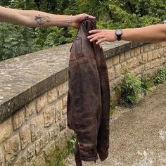 two people holding up an old leather garment