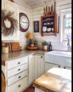 a kitchen with white cabinets and wooden counter tops next to a clock on the wall