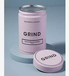 a pink grind coffee can sitting next to a white container with the word grind on it