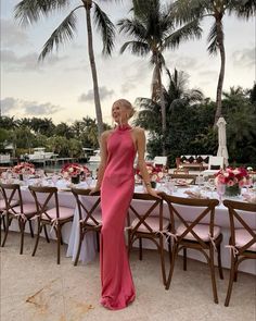 a woman in a pink dress standing next to a table