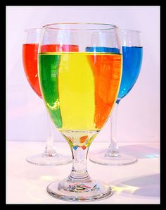 three wine glasses filled with different colored liquid