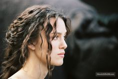 a woman with wet hair looking off into the distance while standing in front of an animal