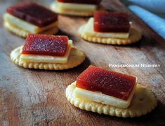 small crackers with jam on them sitting on a cutting board