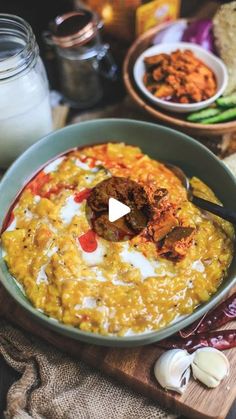 a bowl filled with food sitting on top of a wooden cutting board next to other foods