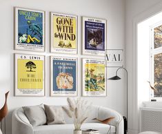 a living room filled with white furniture and posters on the wall above it's windows