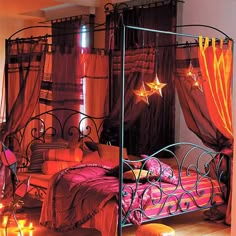 a bedroom decorated in orange and pink colors with candles on the floor, curtains over the bed