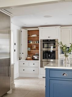 a kitchen with white cabinets and blue island