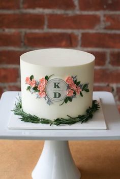 a white cake with pink flowers and greenery on top