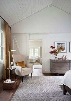 a living room with white walls and wood flooring is pictured in this image, there are two chairs on either side of the bed