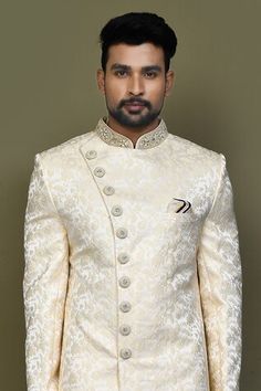 Gold full sleeves asymmetric hem and placket sherwani crafted in imported jacquard silk with all over flora garden pattern and hand embroidery on the band collar neckline and buttons. Paired with an off white dupion art silk Aligadhi pant. - Aza Fashions Bandhgala With Naqshi For Reception, Designer Brocade Bandhgala For Eid, Designer Brocade Sherwani For Eid, Elegant Formal Nehru Jacket With Self Design, Eid Formal Self Design Bandhgala, Elegant Formal Bandhgala With Self Design, Long Sleeve Sherwani With Pallu For Reception, Elegant Designer Bandhgala With Self Design, Elegant Ceremonial Bandhgala With Self Design