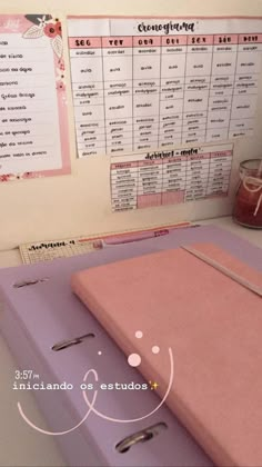 a pink binder sitting on top of a desk next to a pen and paper