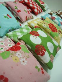 a bunch of pillows that are sitting on a table together, all in different colors and patterns