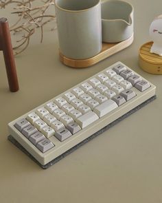 a computer keyboard sitting on top of a table next to a cup and saucer