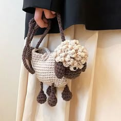 a hand holding a crocheted sheep purse