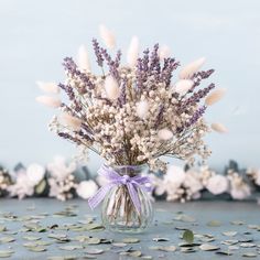 a vase filled with lots of purple and white flowers on top of a blue table