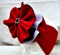 a red, white and black hair bow with a diamond brooch attached to it