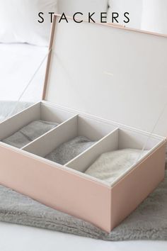 an open pink box sitting on top of a bed next to pillows and pillow cases