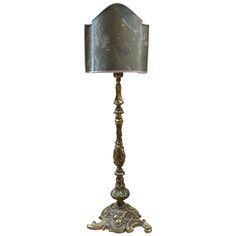 an ornate metal lamp with a silver shade on the top and bottom half of it