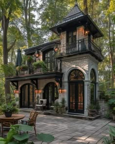 a large house in the middle of a forest with lots of trees and plants around it