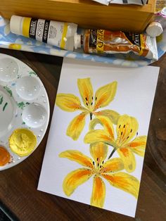 a painting with yellow flowers on it next to some paint and other items that are sitting on a table