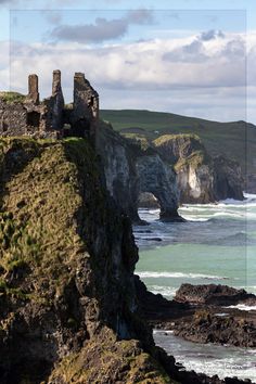 an old castle sitting on top of a cliff next to the ocean