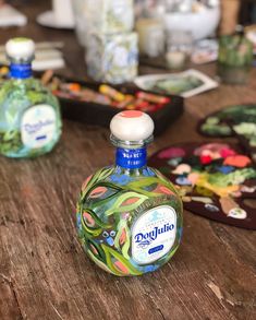 a bottle of alcohol sitting on top of a wooden table next to other bottles and paintbrushes