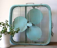 a blue fan sitting on top of a table next to a potted plant