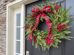 a wreath on the front door of a house with red berries and green fern leaves