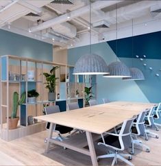 an empty conference room with blue walls and wooden tables in the center, along with hanging plants