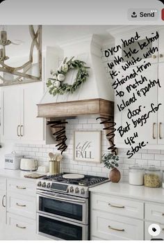 a kitchen with white cabinets and a stove top oven under a wreath on the wall