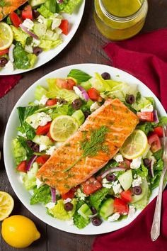 two plates with salmon and salad on them