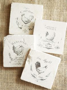 four stone coasters with chickens on them sitting on a burlock cloth background