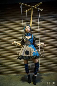 a woman dressed in costume is suspended by strings with wires attached to her body and head