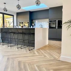 a modern kitchen with an island counter and bar stools in the middle of it