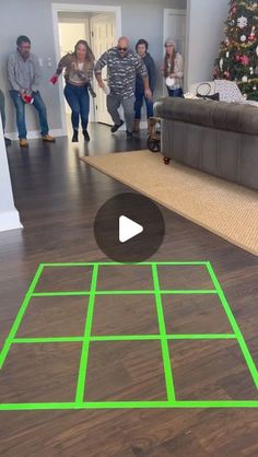 a group of people standing around a living room with a green line on the floor